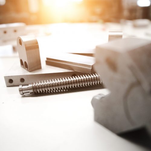Industry 101 / Metallstücke und Bauteile liegen auf dem Montagetisch - Technische Teile - Gewinde - Bohrungen - Schrauben - Metallstücke